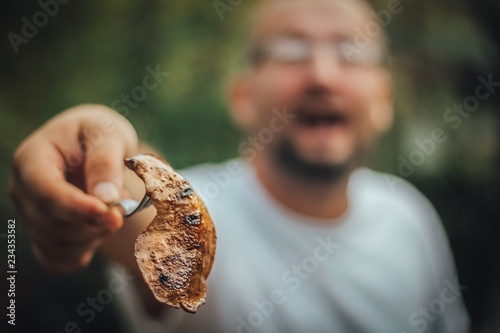 Man with open mouth showing you meat from the grill, outdoor barbecue, copy space