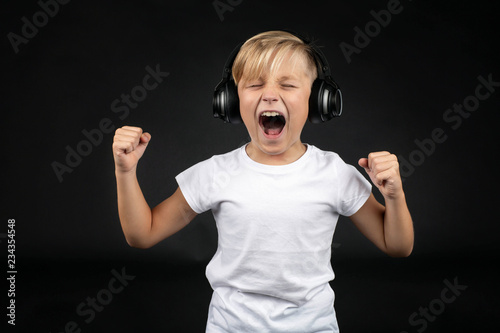 Little blond boy screams loudly with a headphone