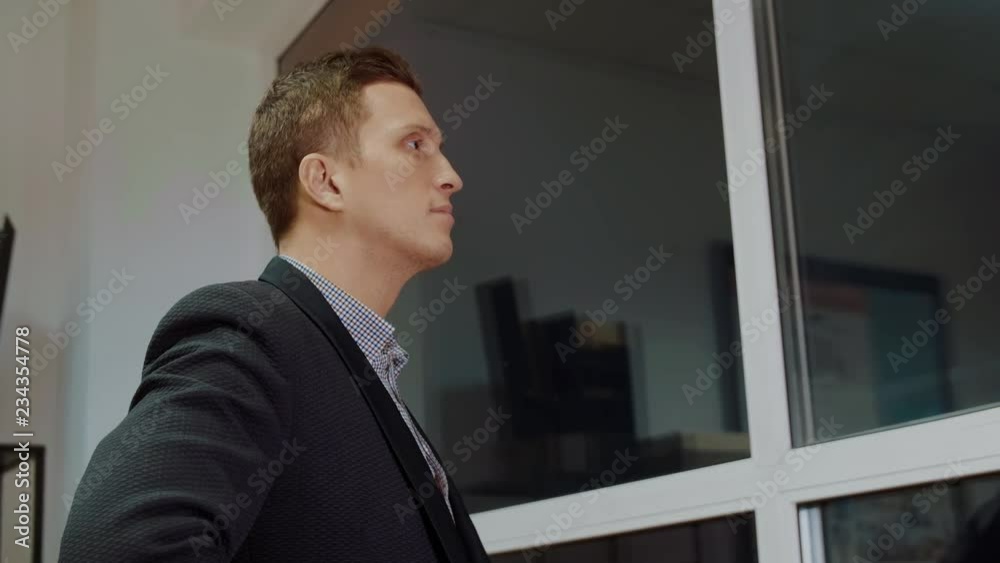 A man looks at the evening city through the window of a skyscraper office closeup view A man looks at the evening city through the window of a skyscraper office closeup view