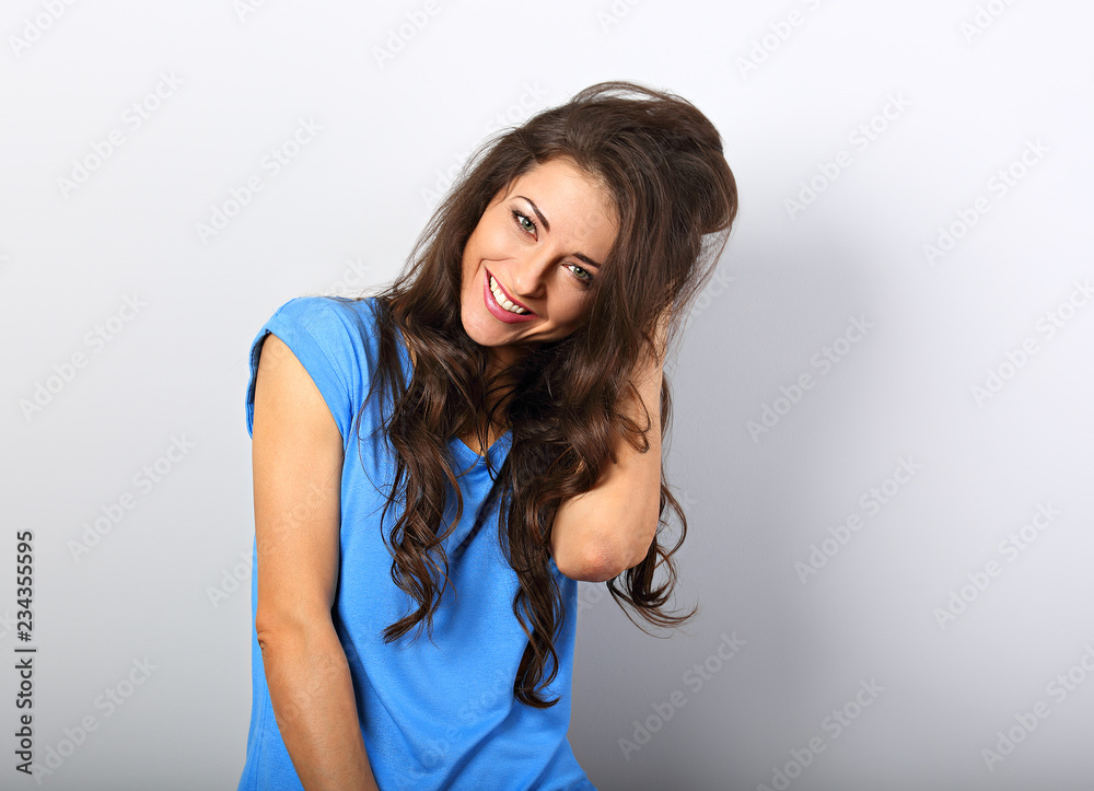 Beautiful excited laughing woman looking with happy smile in blue shirt with long curly hairstyle. Closeup portrait with empty copy space. Beautiful excited laughing woman looking with happy smile in blue shirt with long curly hairstyle. Closeup portrait with empty copy space.