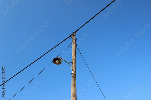 Old street lamp post electricity pole wires wooden blue sky