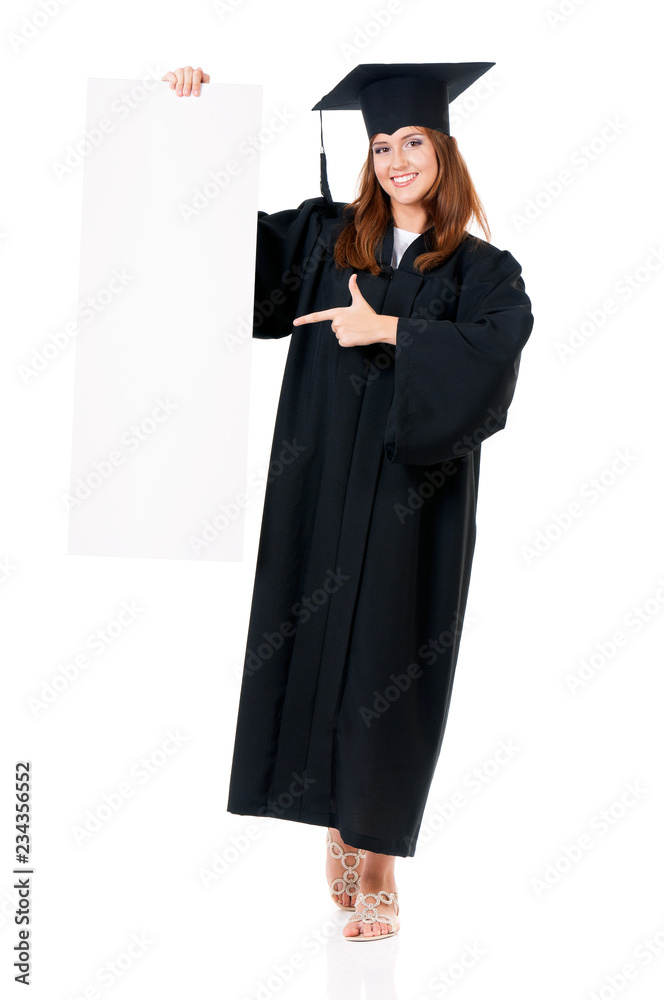 Beautiful graduate female student in mantle showing blank placard board. Full length portrait of caucasian teen girl isolated on white background Beautiful graduate female student in mantle showing blank placard board. Full length portrait of caucasian teen girl isolated on white background
