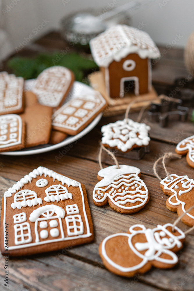 A lot of ginger biscuits in different form on brown wooden table. Decorated with white sweet glaze. Christmas mood, winter morning. Fir branches and forms for baking A lot of ginger biscuits in different form on brown wooden table. Decorated with white sweet glaze. Christmas mood, winter morning. Fir branches and forms for baking