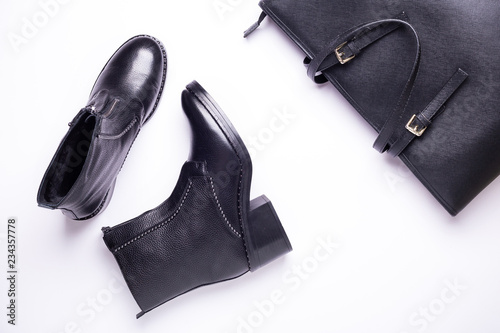 Woman accessory. Black stylish boots, black luxury leather bag on white background. Top view background. Flat lay. Copy space.