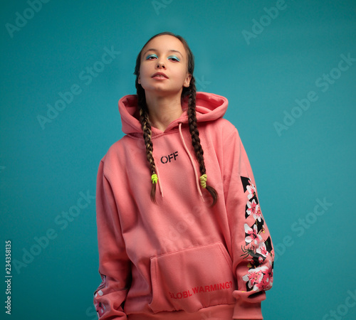 girl with pigtails in a pink jacket posing against a background with flowers