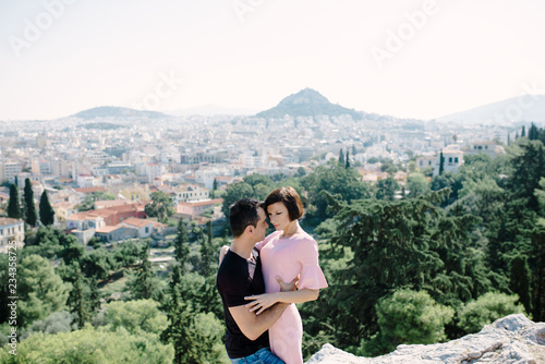 couple have a date on the peak of the hill with panorama view on the city kissing each other