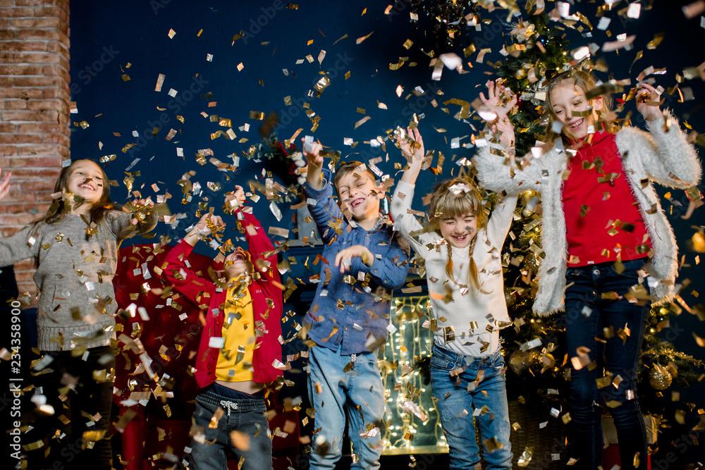 Happy little five Caucasian kids throw confetti and celebrating Christmas. Winter holidays and New Year concept