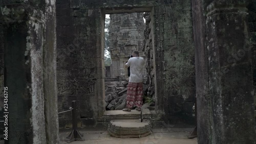 Man standing in old ruins and doing photos on camera  photo