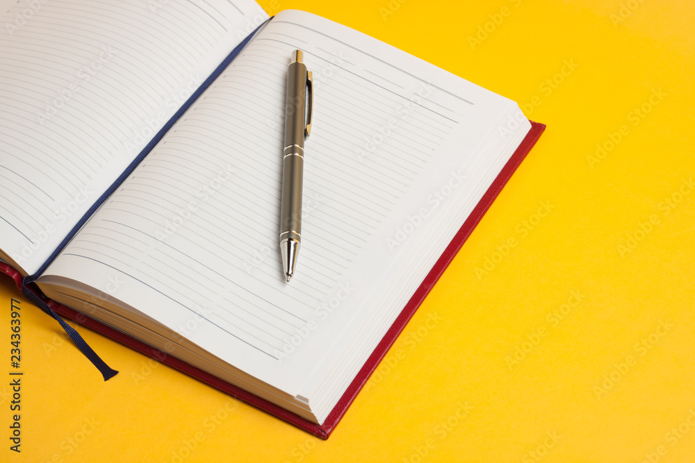 concept business time is money, a new beautiful red notebook and pen for responsible people on a bright yellow background concept business time is money, a new beautiful red notebook and pen for responsible people on a bright yellow background