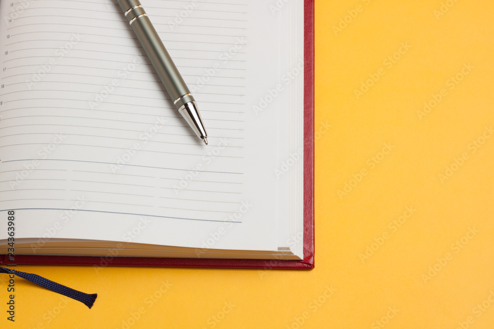 concept business time is money, a new beautiful red notebook and pen for responsible people on a bright yellow background concept business time is money, a new beautiful red notebook and pen for responsible people on a bright yellow background