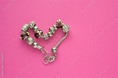 Heart shape silver bracelet with unique decoration and stones on pink background. Best gift for girl for womans day and saint valentine. Jewellery decor.