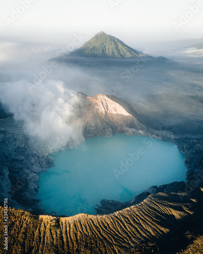 Blue volcanic crater lake with mountain peak fog photo