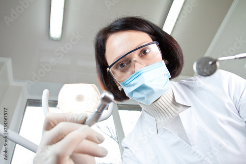 Doctor dentist in mask looks at patient