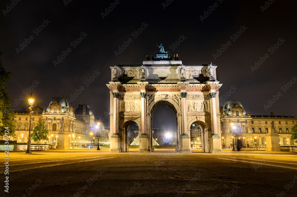 Triumphal Arch (Arc de Carrousel) and Louvre museum at background at night in Paris, France