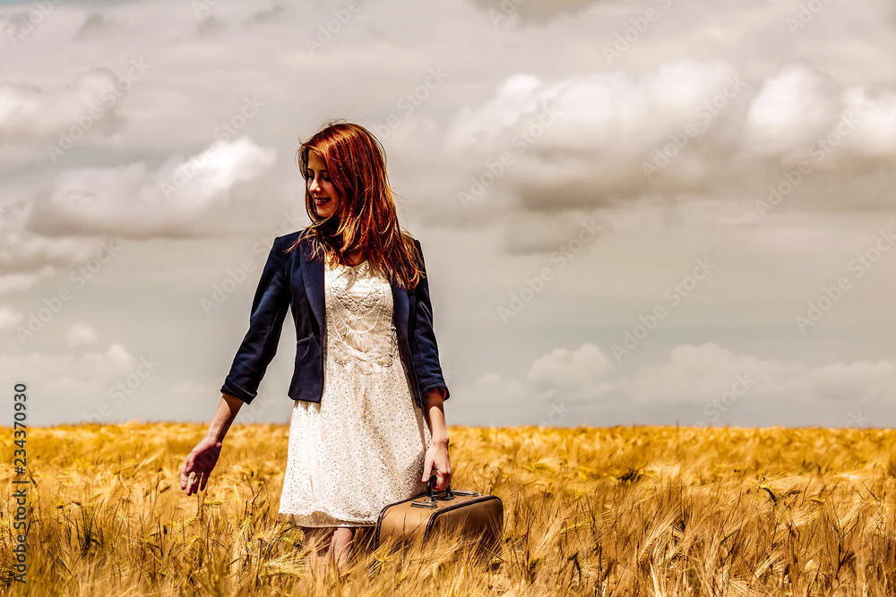 Young girl in white dress and black jacket with suitcase stay at wheat field. Young girl in white dress and black jacket with suitcase stay at wheat field.