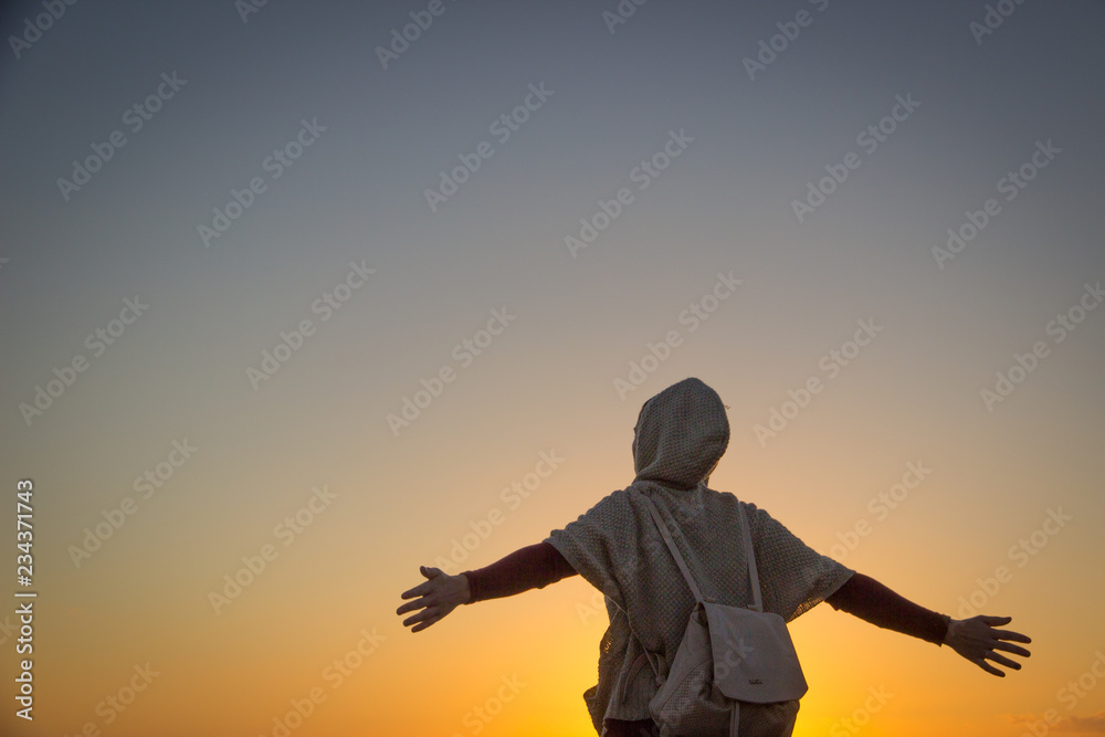 Fototapeta premium silueta de una mujer viajera con mochila a contraluz en un amanecer o atardecer
