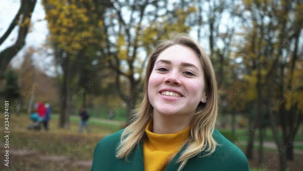 Autumn portrait of beautiful woman over yellow leaves while walking in the park in fall. The camera pans around the young woman. Girl is spinning. Blonde young girl in a green coat. Autumn portrait of beautiful woman over yellow leaves while walking in the park in fall. The camera pans around the young woman. Girl is spinning. Blonde young girl in a green coat.