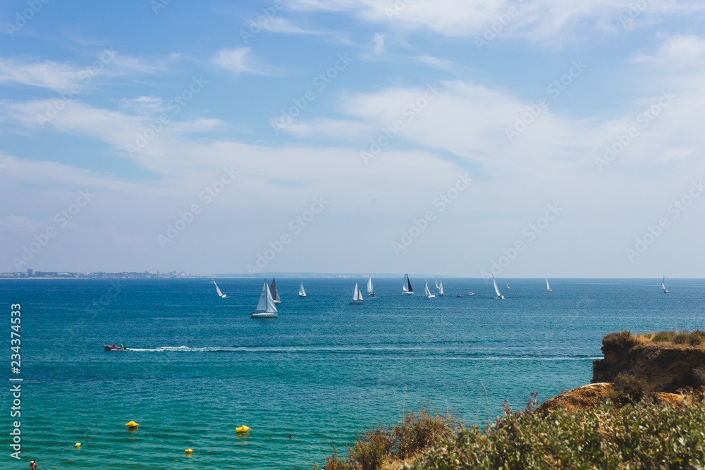 Lots of sailboats sailing in the ocean near the coast of Lagos, Portugal