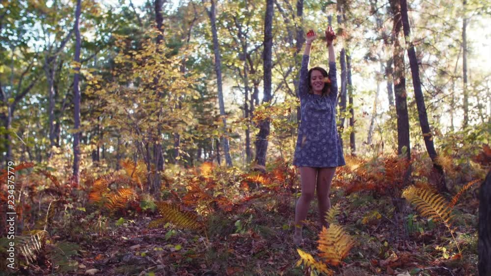 Slow motion of young woman dancing and playing with leaves in autumn forest Slow motion of young woman dancing and playing with leaves in autumn forest