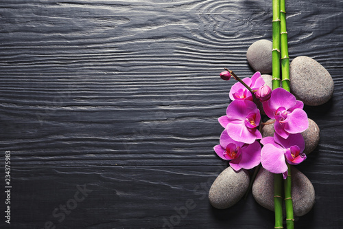 Photography Spa stones with orchid flowers and bamboo on dark wooden background, top view