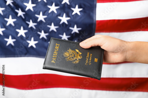 Woman holding passport against flag of USA, closeup