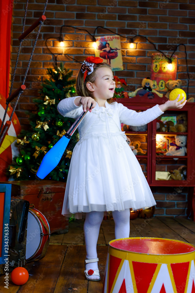 girl juggles with bits against the background of the Christmas tree. Circus number.