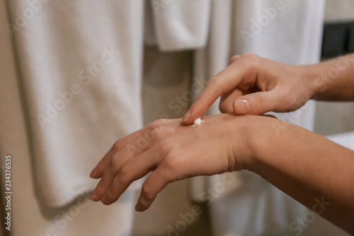 Woman applying hand cream in bathroom, closeup