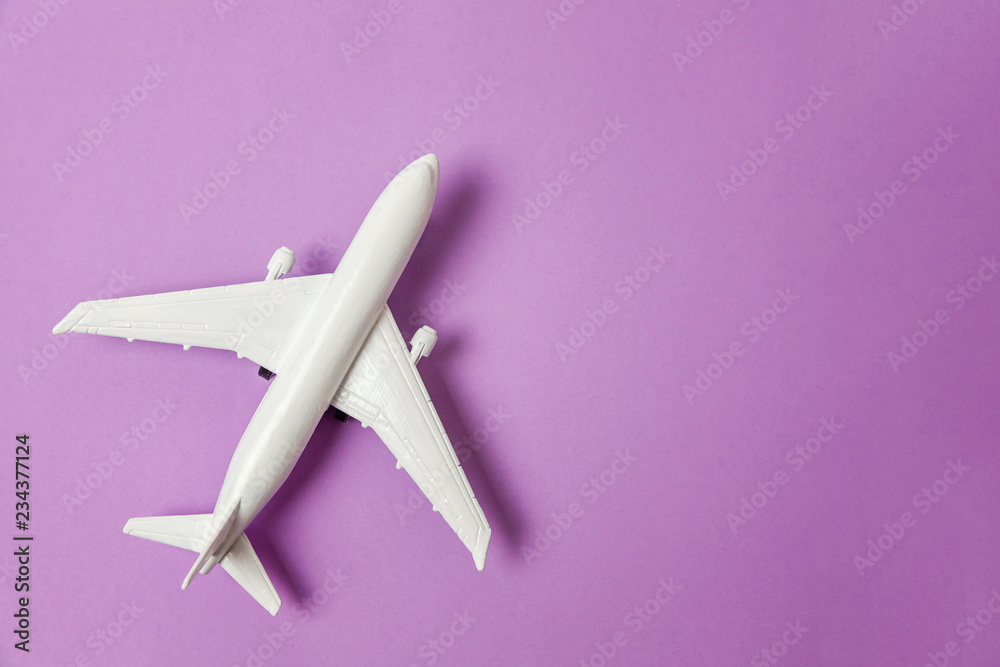 Fototapeta Simply flat lay design miniature toy model plane on violet purple pastel colorful paper trendy background. Travel by plane vacation summer weekend sea adventure trip journey ticket tour concept