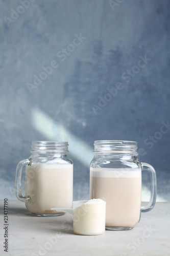 Mason jars with protein shake and scoop of powder on table. Space for text