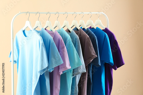 Men's clothes hanging on wardrobe rack against light background