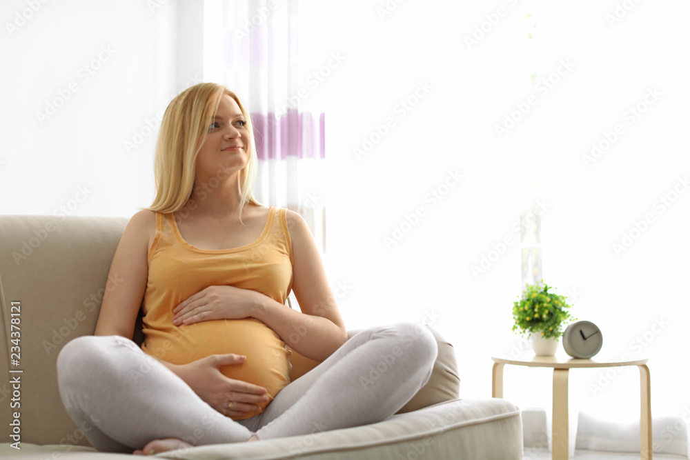 Beautiful pregnant woman sitting on sofa at home Beautiful pregnant woman sitting on sofa at home