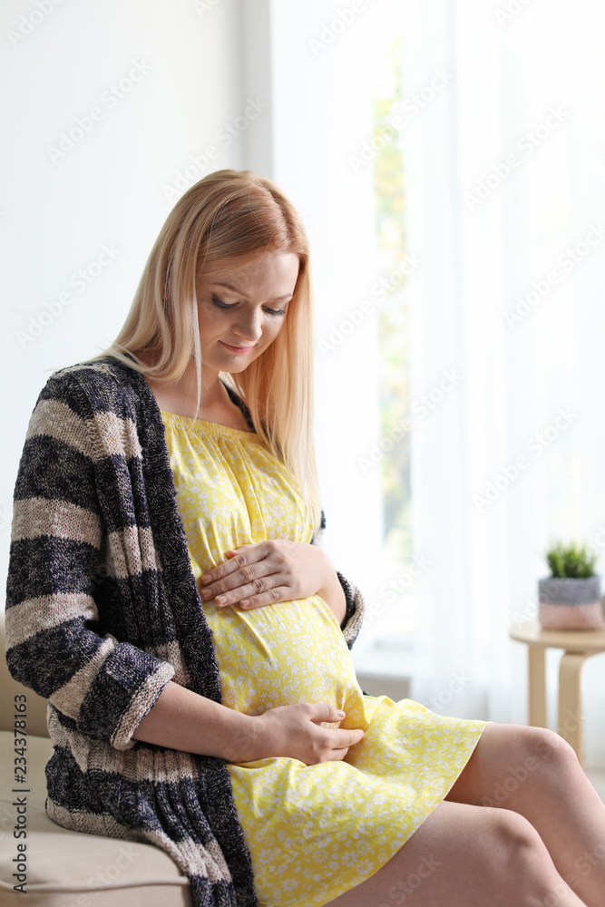 Beautiful pregnant woman sitting in light room at home Beautiful pregnant woman sitting in light room at home