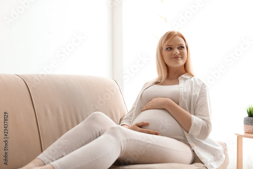 Beautiful pregnant woman resting on sofa at home © New Africa
