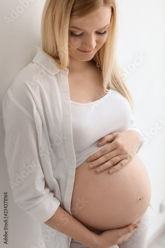 Free Download Portrait of beautiful pregnant woman near light wall - GFXLoad