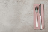 Fork, knife and linen napkin on grey background, top view. Space for text