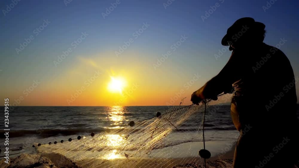 Fishermen fishing in the early morning golden light manual hand pulling the net