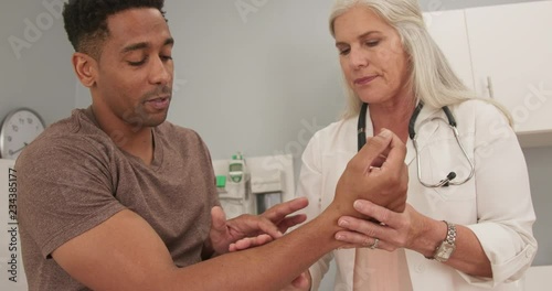 Wallpaper Mural Portrait of young black male consulting with female senior doctor about wrist pain. Close up of african-american male talking to mature doctor about arm injury Torontodigital.ca