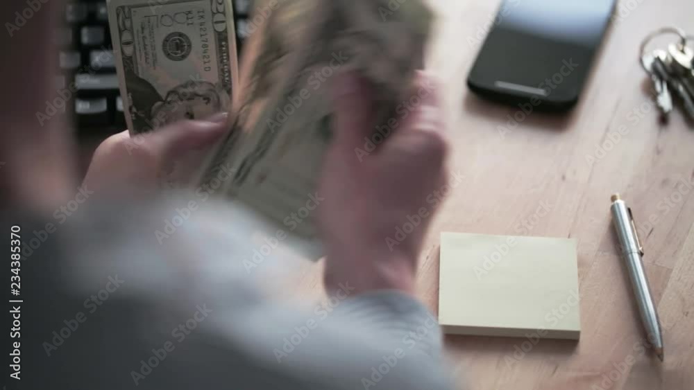 A female accountant counts American dollar bills and writes down the amount on a sticky note. A female accountant counts American dollar bills and writes down the amount on a sticky note.