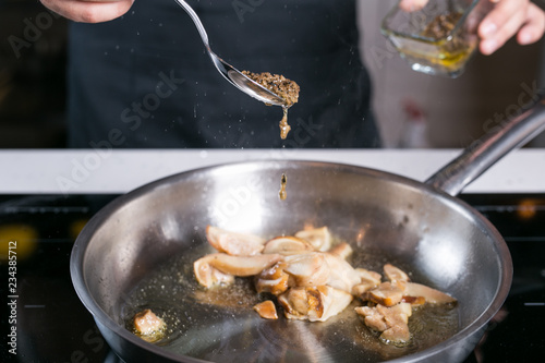 Chef pouring truffle oil over cooking mushrooms