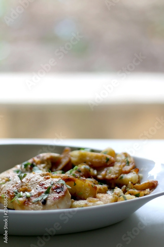 Roasted chicken and Lyonnaise potatoes. Lyonnaise potatoes are sliced pan-fried potatoes with onion, parsley, butter and garlic. Selective focus.
