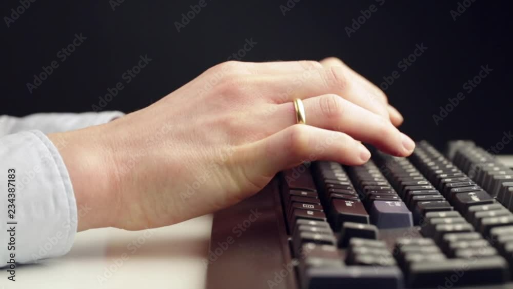 Low angle, side view dolly shot of a young businesswoman typing on a black computer keyboard on a white office desk. Low angle, side view dolly shot of a young businesswoman typing on a black computer keyboard on a white office desk.
