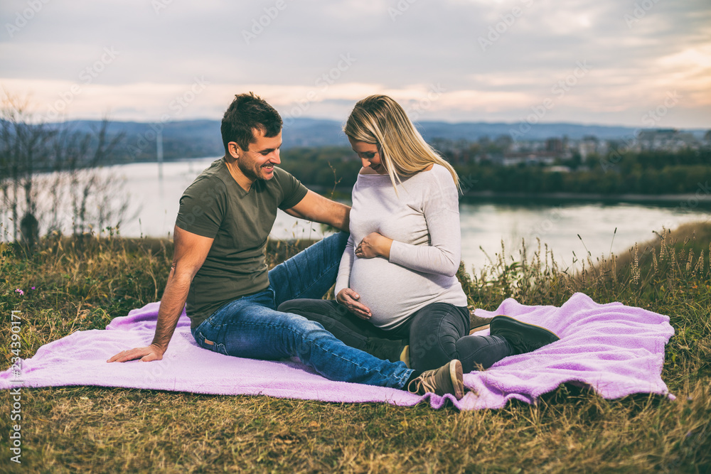 Husband and his pregnant wife enjoy spending time together outdoor.Toned image