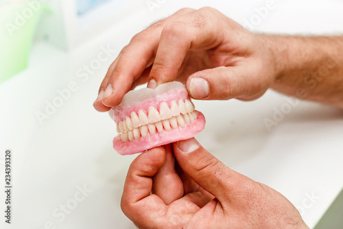 Dental technician holding artificial teeth arrangement of full mouth complete denture