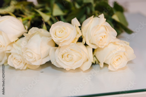 White roses lie on a bright table. Beautiful white flowers. © Sergey_Siberia88