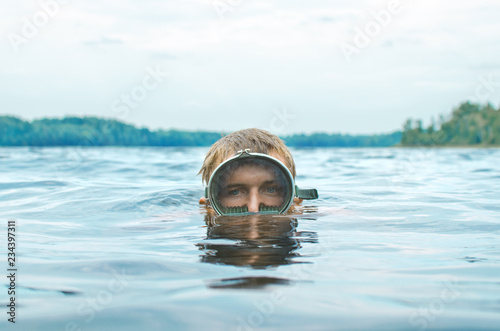 Fotografia man in a mask for scuba diving emerges from the lake, head close-up