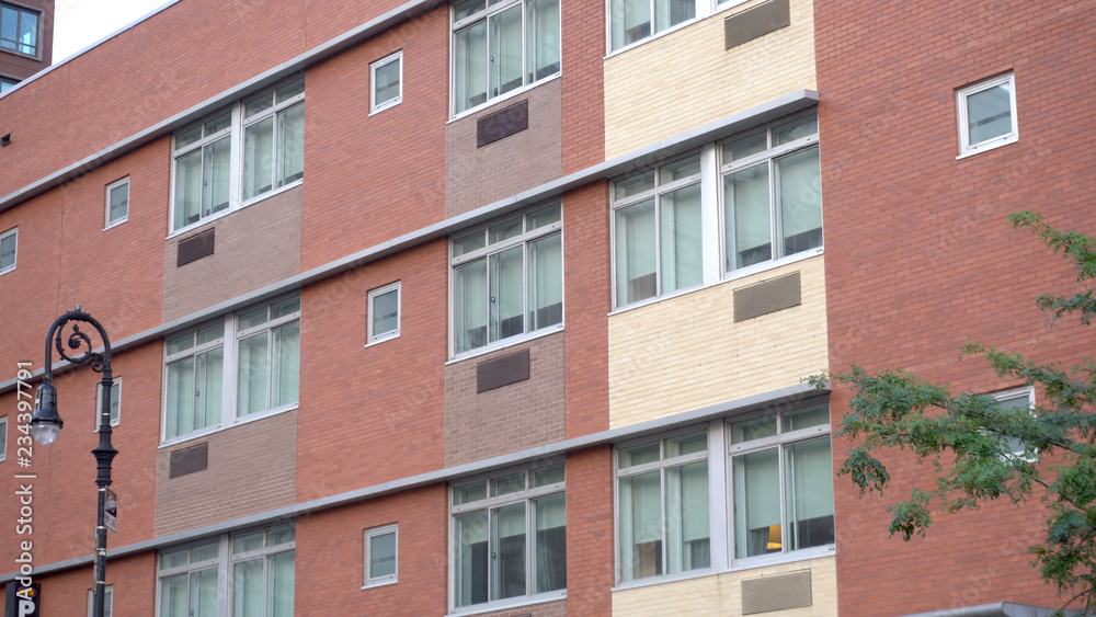 Fototapeta premium Exterior establishing shot of brick building day time. Apartment office school college dorm style architecture facade. Lock down DX image