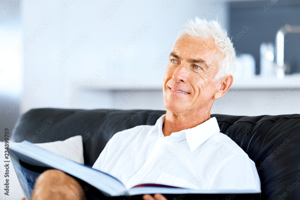 Handsome sennior man reading a book relaxing on a sofa Handsome sennior man reading a book relaxing on a sofa