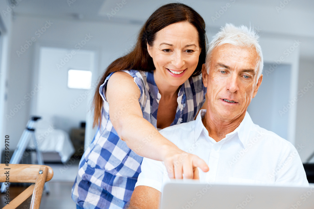 Happy modern mature couple working on laptop at home Happy modern mature couple working on laptop at home