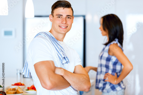 Young man standing in the kitchen and smiling