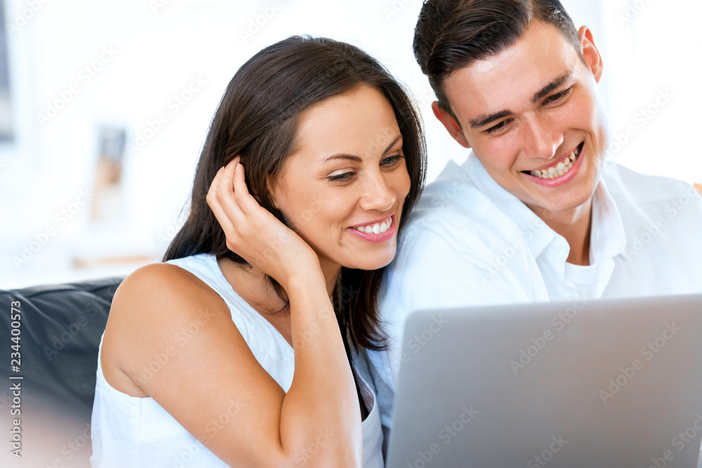 Happy modern couple working on laptop at home Happy modern couple working on laptop at home